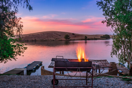 Sunset view of a still, silent dam with camp fire in the foreground,  Club Elani Resort, Cape Town, South Africaの写真素材
