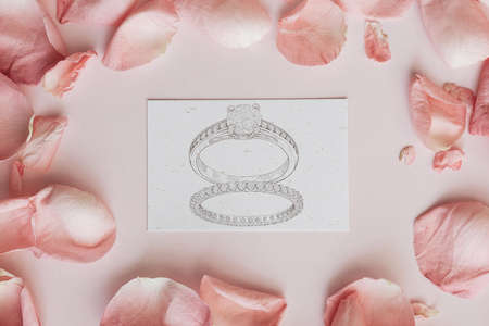 Drawing of diamond rings on a pink background with rose petals. view from above.の写真素材