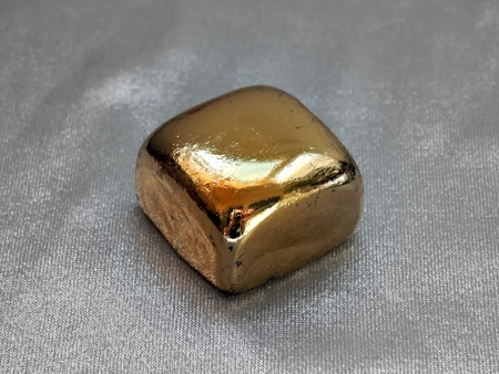 Gold bar from gold leaf on a silvery backgroundの写真素材