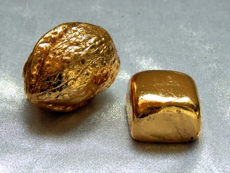 Gold bar with walnut nuts on a silvery backgroundの写真素材