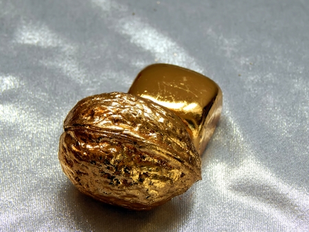 Gold bar with walnut nuts on a silvery backgroundの写真素材