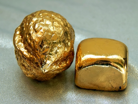 Gold bar with walnut nuts on a silvery backgroundの写真素材