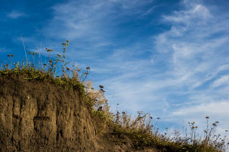 Blue sky with clouds above a grass hillsideの写真素材