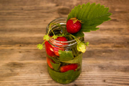retro glass jars of lemonade with strawberries and mint on wooden tableの写真素材
