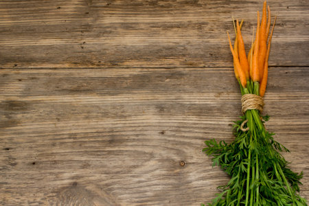 Freshly washed whole carrots on old wooden table. Copy space to right.