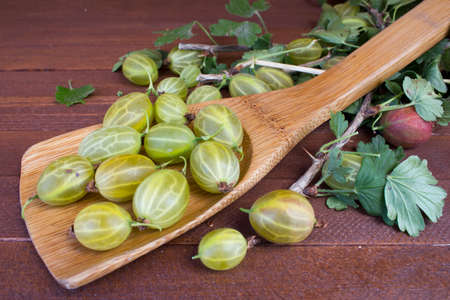 Fresh berries of red and green gooseberries with leaves on the old wooden tableの写真素材