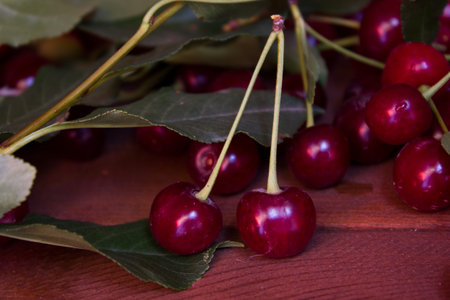Ripe cherries, leaves on wooden table