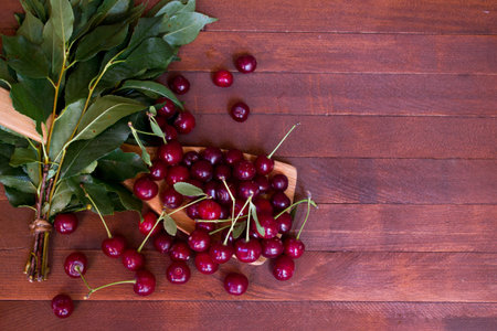 Ripe cherries, leaves on wooden table with copy space