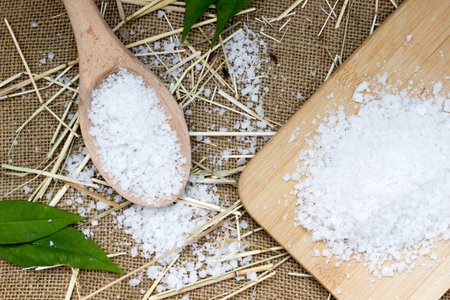 Sea salt in wooden spoon on burlap sack background