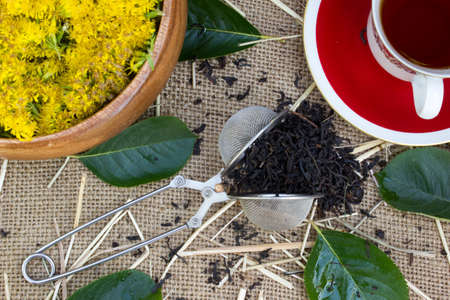 Shot from the dry black tea with flowers , a cup on burlap backgroundの写真素材