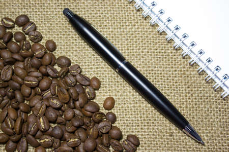 Blank notebook with black pen, coffee beans on top of a burlapの写真素材