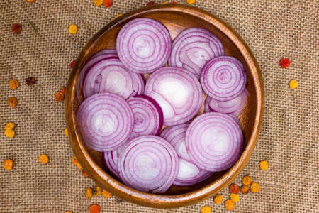 chopped red onions in wooden plate on sackcloth, as backgroundの写真素材