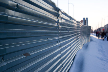 Green metal fence along the winter road
