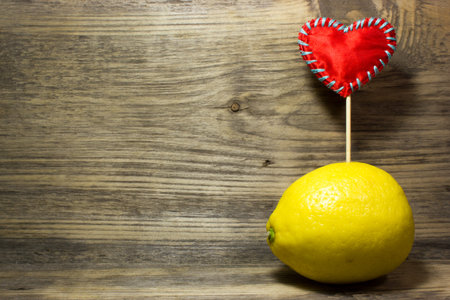 One yellow lemon on wooden background. Free space for text.の写真素材