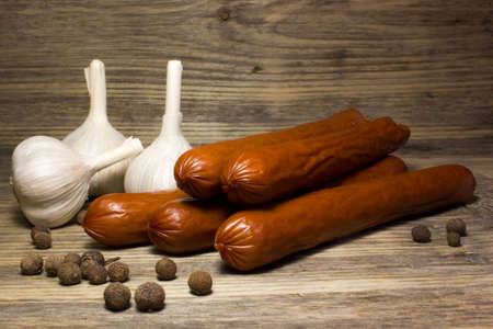 Smoked beer sausage with garlic and spices on wooden background.の写真素材