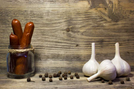 Smoked beer sausage with garlic and spices on wooden background.の写真素材