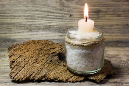 Burning white candle in glass jar on wooden backgroundの写真素材