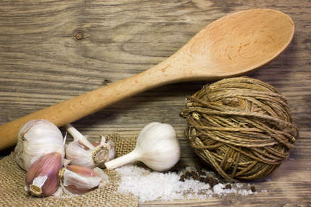 Wooden kitchen spoon, Garlic, sea salt on wooden background. Space for text.の写真素材