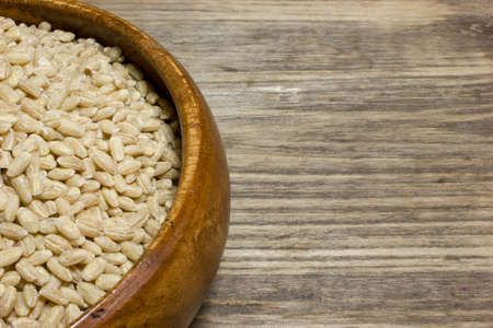 Grain of pearl Barley on a wooden background. Space for text.の写真素材