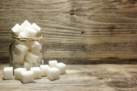 Sugar cubes in glass jar on wooden backgroundの写真素材