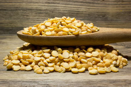 Crushed dry peas in wooden spoon on wooden backgroundの写真素材