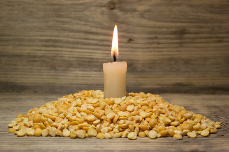 Crushed dried peas and burning candle on wooden backgroundの写真素材