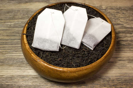 Dry tea leaves for black tea and paper tea bag on wooden backgroundの写真素材