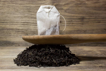 Dry tea leaves for black tea and paper tea bag on wooden backgroundの写真素材