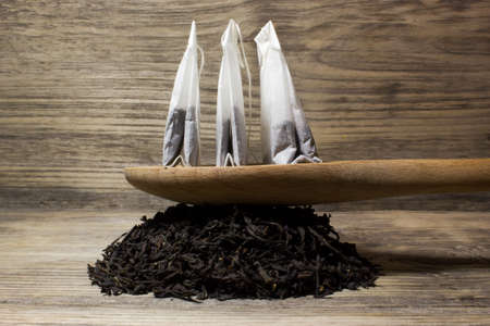 Dry tea leaves for black tea and paper tea bag on wooden backgroundの写真素材