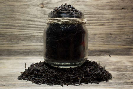 Dry tea leaves for black tea and glass jar on wooden backgroundの写真素材