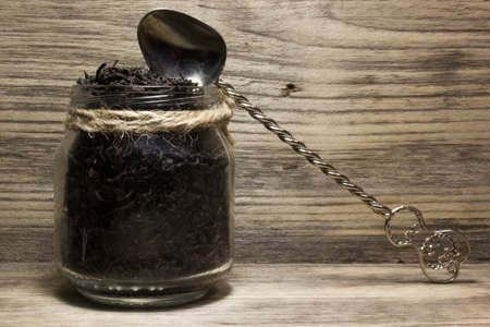 Dry tea leaves for black tea and glass jar on wooden backgroundの写真素材