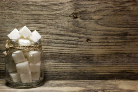 Sugar cubes in glass jar on wooden backgroundの写真素材