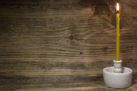Church burning candle on wooden backgroundの写真素材