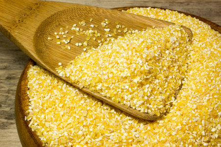Corn grits and wooden spoon on wooden backgroundの写真素材