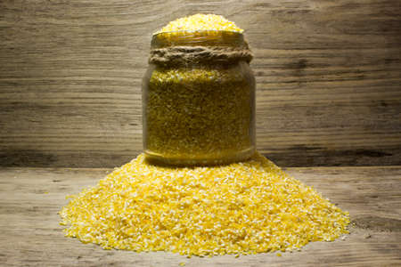 Corn grits and glass jar on wooden backgroundの写真素材