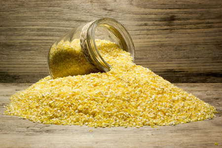 Corn grits and glass jar on wooden backgroundの写真素材