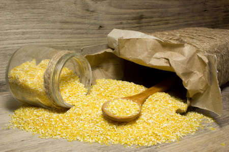 Corn grits and wooden spoon on wooden backgroundの写真素材