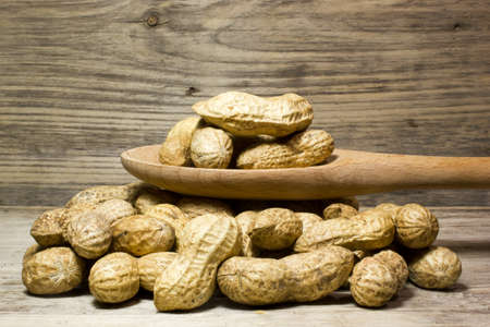 Peanuts in shell and wooden spoon on wooden backgroundの写真素材