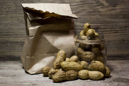 Peanuts in shell and glass jar on wooden backgroundの写真素材