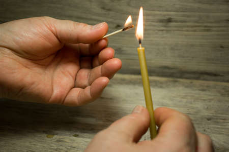 A lighted match in his hand and the candle, Matches with blue heads on wooden backgroundの写真素材