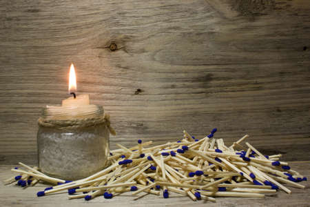 A lighted candle, Matches with blue heads on wooden backgroundの写真素材