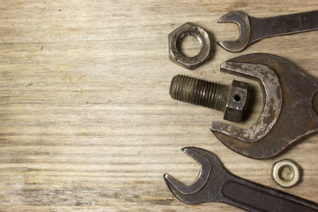 Wrench, nuts and bolts on wooden background