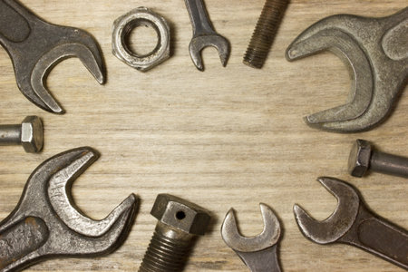 Wrench, nuts and bolts on wooden background