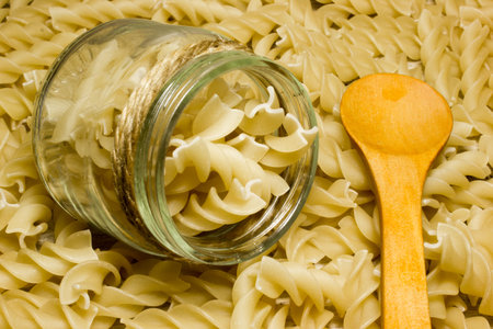 Spiral noodles and wooden spoon on wooden background