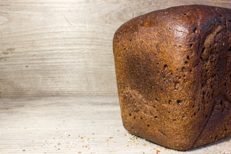Black rye bread on wooden background.