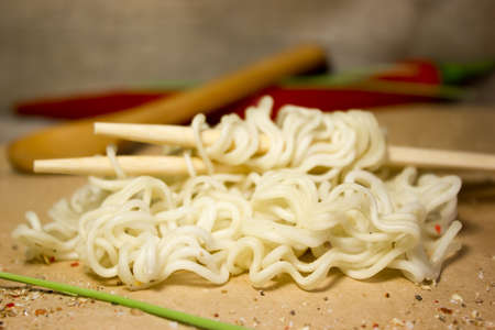 Instant noodles in a wooden bowl with chopsticks. Wooden background and red pepper.の写真素材