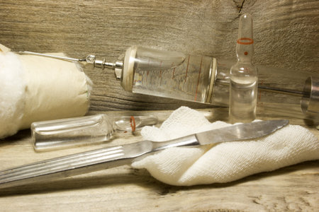 Iron vintage glass syringe with needles on a wooden background.