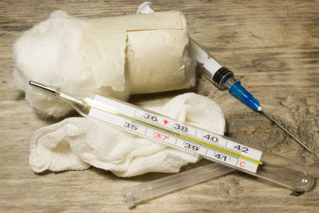 Plastic disposable syringe and thermometer on wooden background.の写真素材