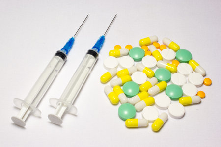 Medical syringe and pills on white background