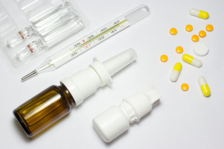 Medical thermometer and pills on white background